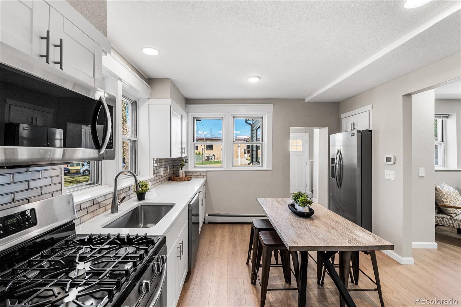 2259 Depew Street Edgewater, CO 80214 - Photo 11 of 46 a kitchen with stainless steel appliances a dining table chairs stove refrigerator and cabinets