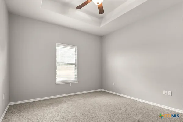 an empty room with chandelier fan and windows