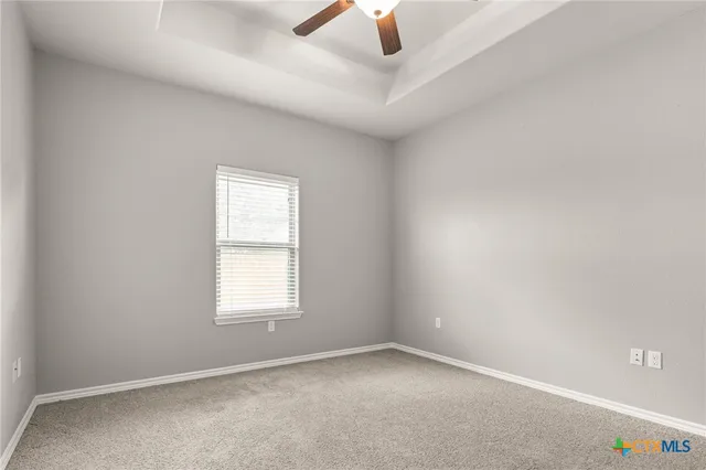 an empty room with chandelier fan and windows