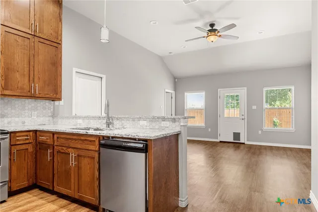 a kitchen with granite countertop a sink a counter top space and cabinets