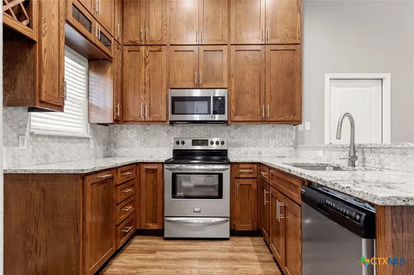 a kitchen with stainless steel appliances granite countertop a sink stove and microwave