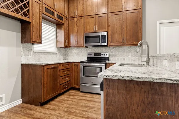 a kitchen with stainless steel appliances granite countertop a sink a stove and microwave