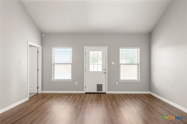 an empty room with wooden floor and windows