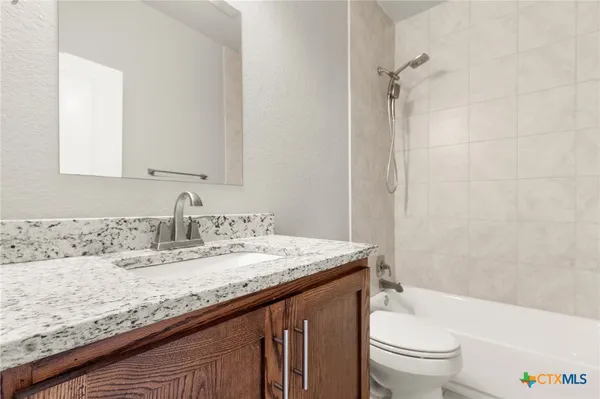 a bathroom with a granite countertop sink a toilet and shower