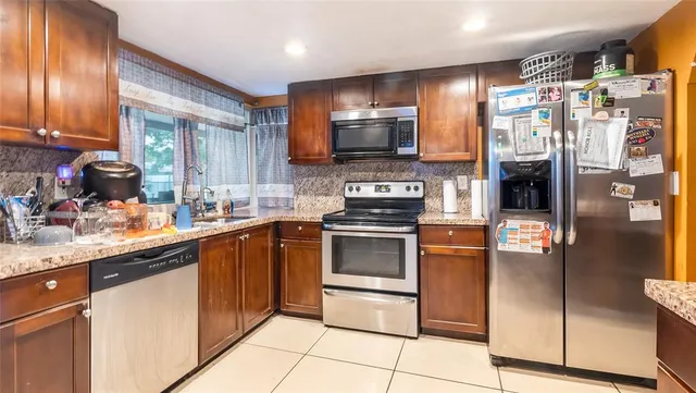 a kitchen with stainless steel appliances granite countertop a refrigerator a stove and a sink