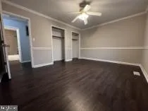 an empty room with wooden floor cabinet and windows