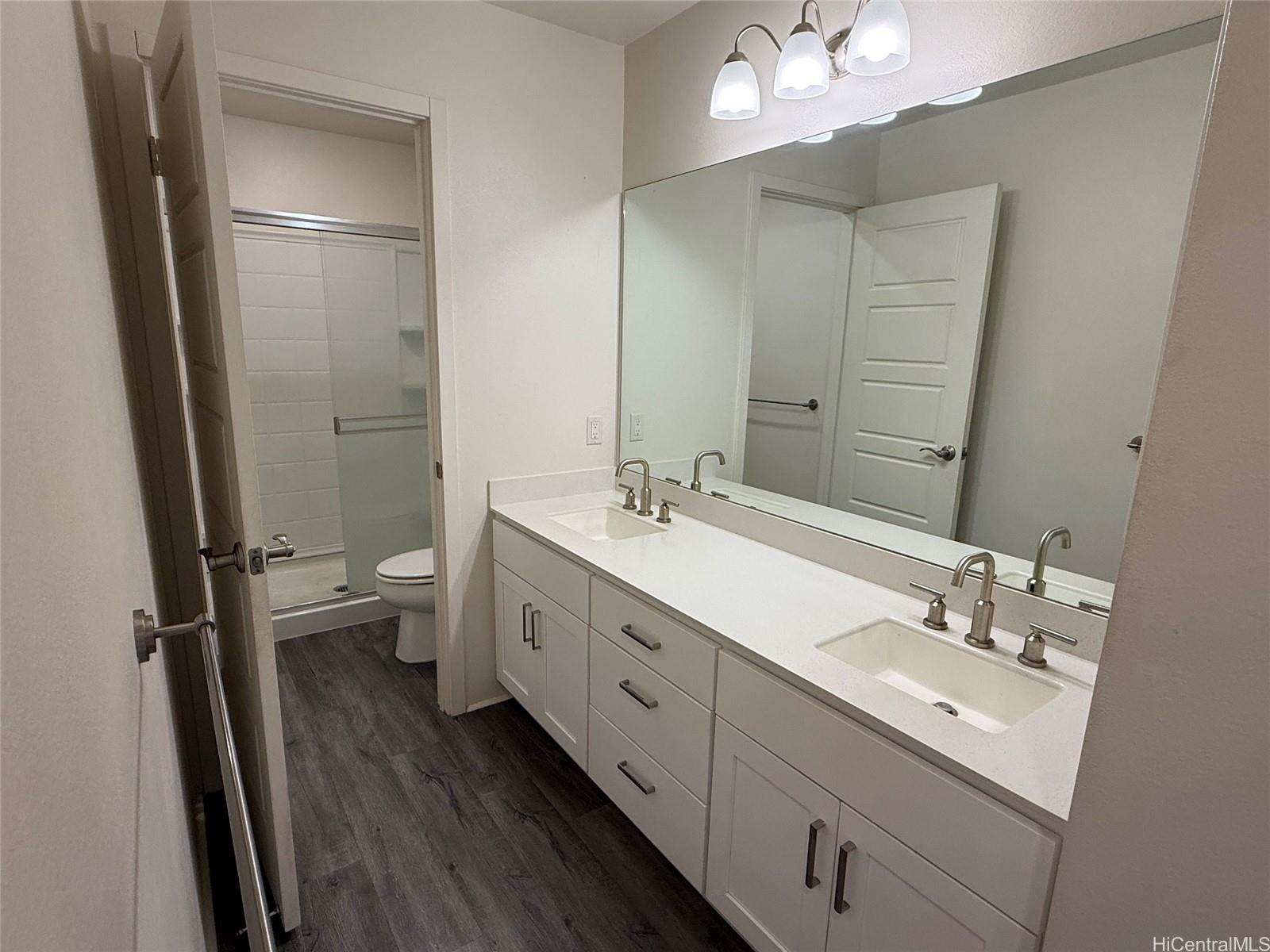 91-3524 Iwikuamo'o Street, Unit 102 Ewa Beach, HI 96706 - Photo 18 of 25 a spacious bathroom with a double vanity sink a toilet and a mirror
