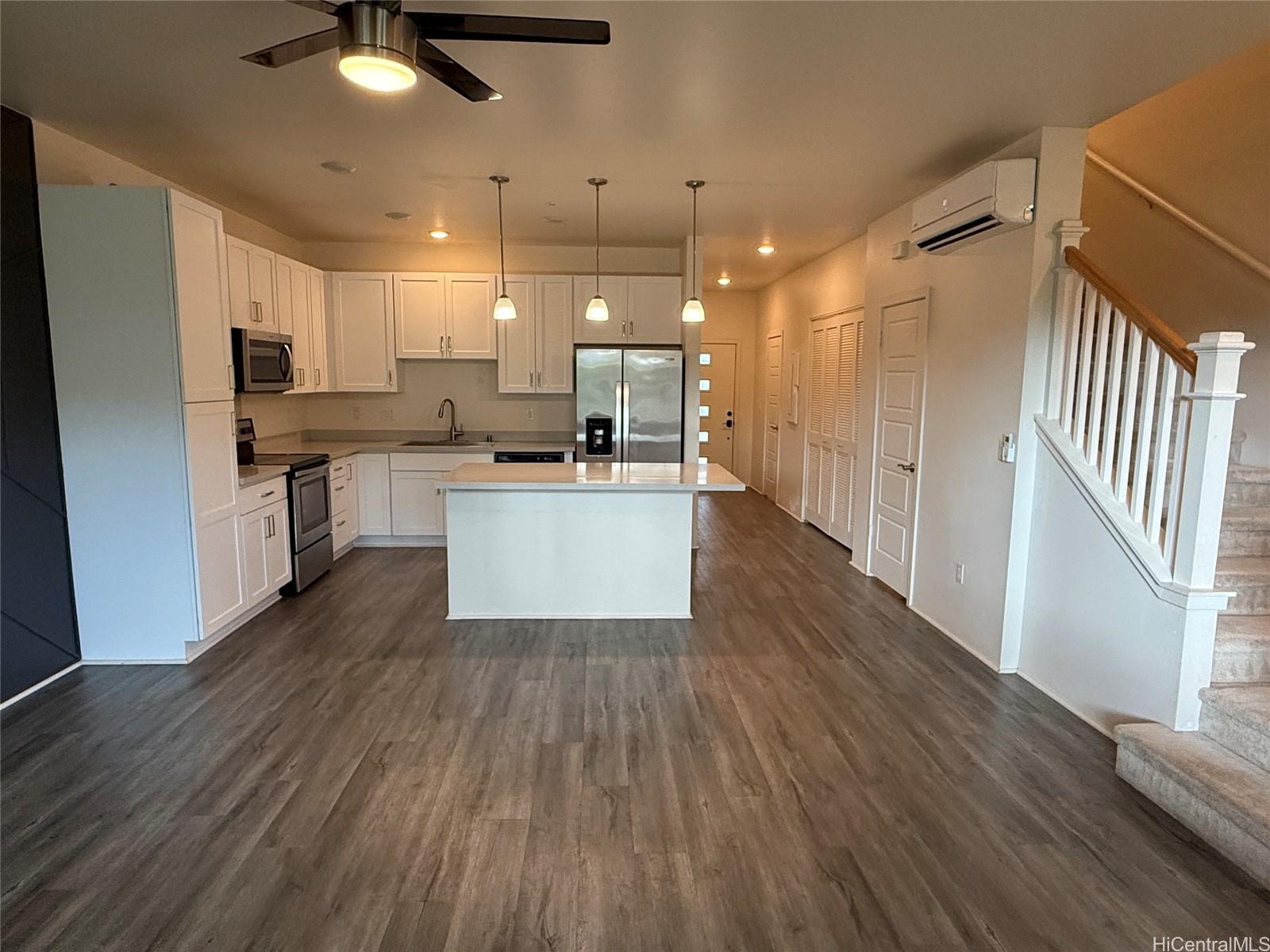 91-3524 Iwikuamo'o Street, Unit 102 Ewa Beach, HI 96706 - Photo 5 of 25 a kitchen with stainless steel appliances granite countertop a refrigerator a sink dishwasher a stove and white countertops with wooden floor