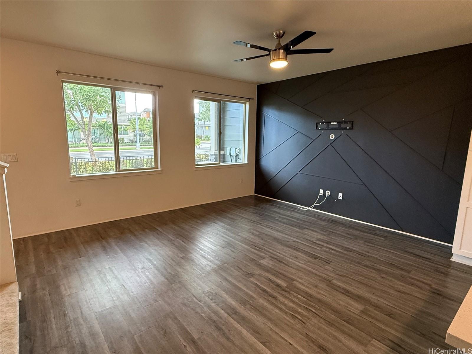 91-3524 Iwikuamo'o Street, Unit 102 Ewa Beach, HI 96706 - Photo 8 of 25 an empty room with wooden floor chandelier fan and windows
