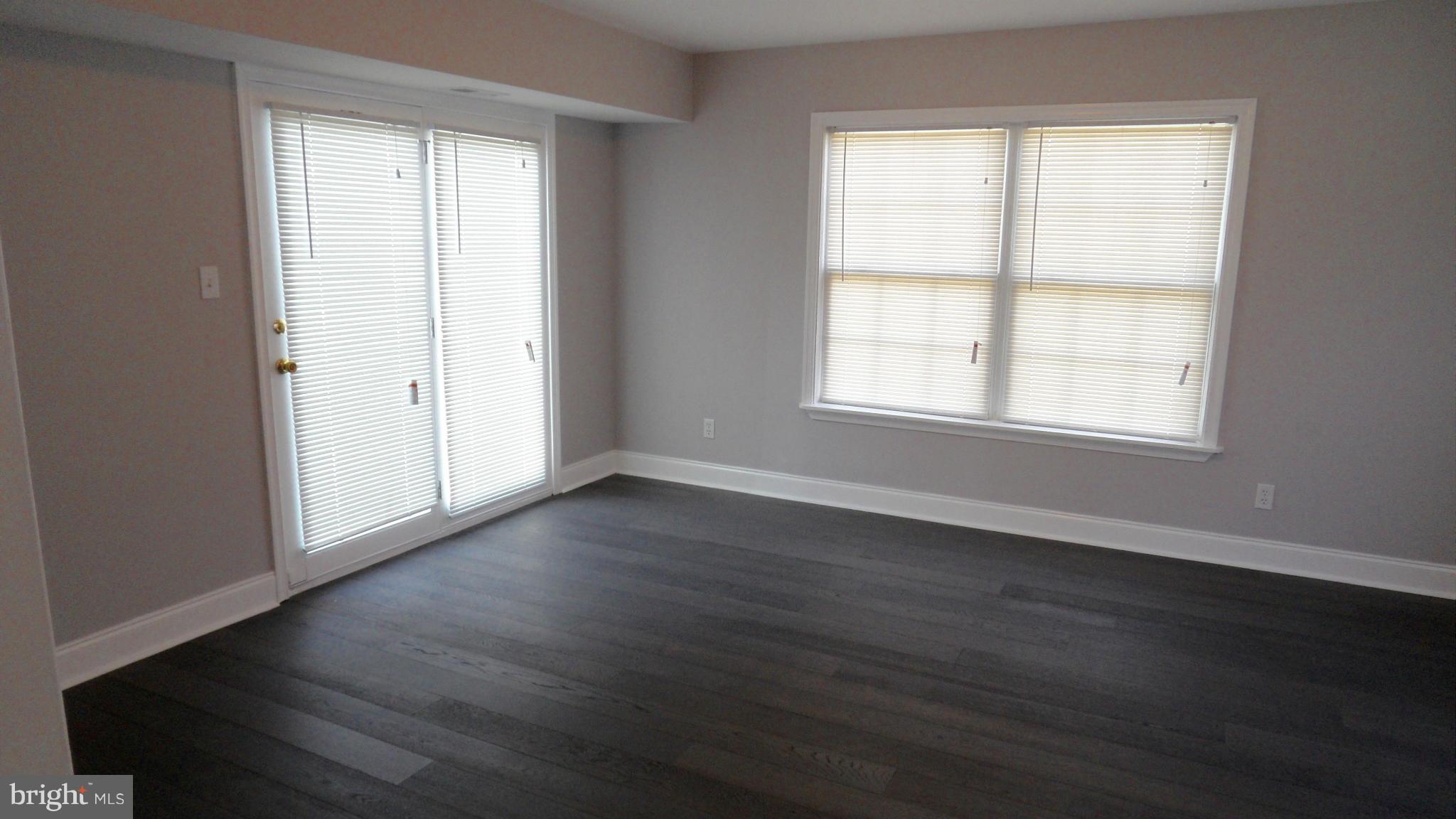 3832 Byfield Road Baltimore, MD 21207 - Photo 6 of 30 an empty room with wooden floor and windows