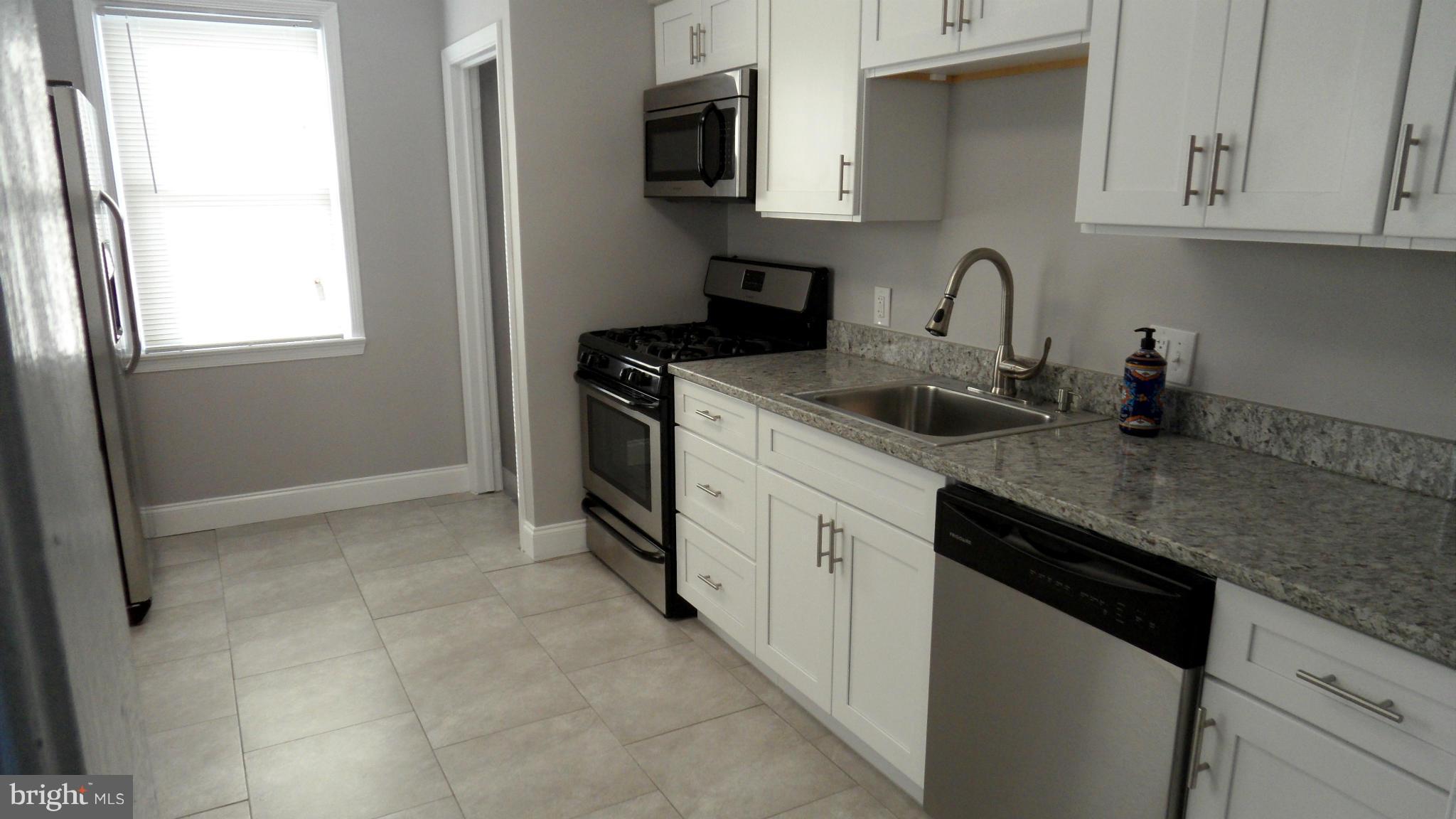 3832 Byfield Road Baltimore, MD 21207 - Photo 9 of 30 a kitchen with stainless steel appliances granite countertop a sink stove and microwave