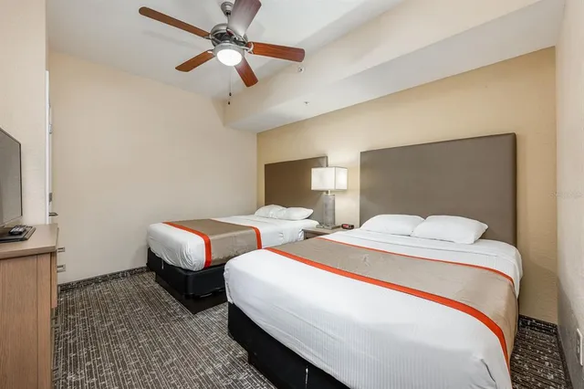 a bedroom with two beds and ceiling fan
