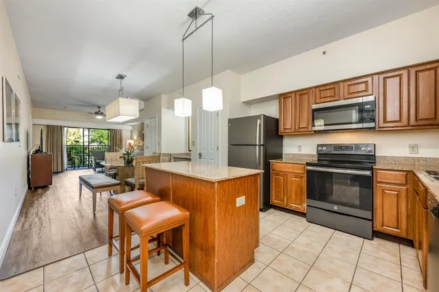 a kitchen with a refrigerator a stove top oven a sink dishwasher and a dining table with wooden floor