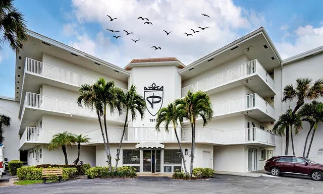 a front view of building with palm trees