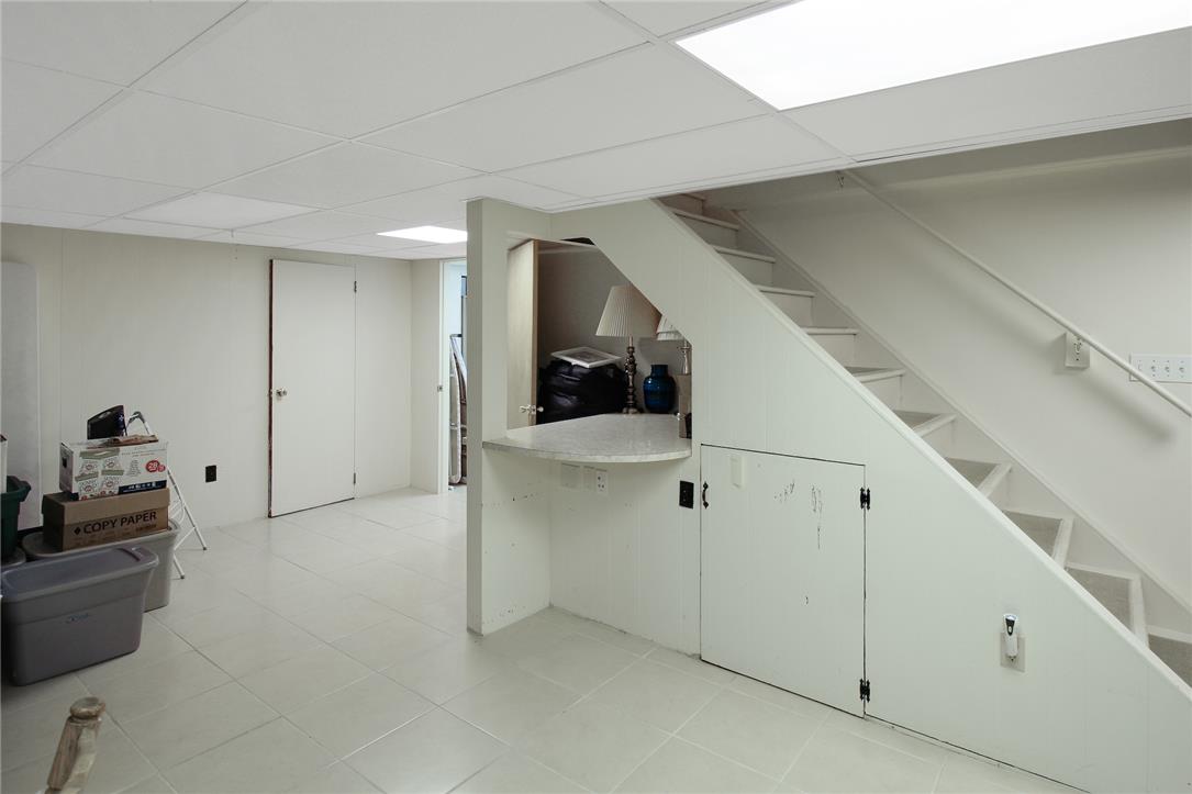 1256 Ridge Avenue Whitehall, PA 18052 - Photo 36 of 43 A well-lit, functional basement with white walls and a tiled floor, featuring a stairway with under-stair storage.