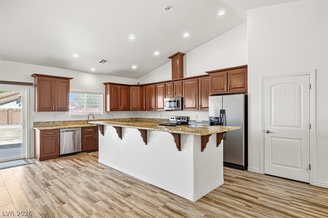 6720 Stubblefield Drive Pahrump, NV 89061 - Photo 12 of 51 A well-equipped kitchen features a generous island, granite countertops, and wood look tile flooring.