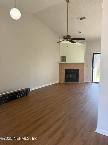 a view of empty room with wooden floor and ceiling fan