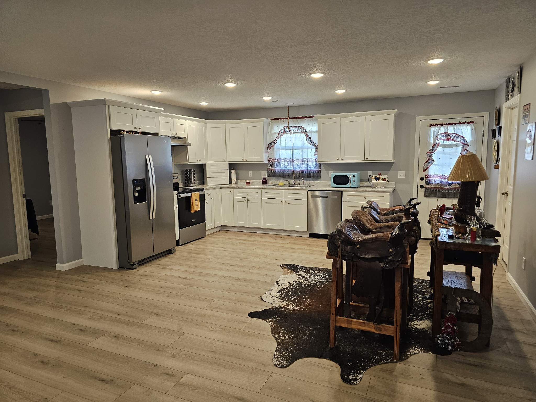 110 Water Street Big Sandy, TN 38221 - Photo 5 of 14 a kitchen with stainless steel appliances kitchen island granite countertop a refrigerator oven a sink a dining table and chairs with wooden floor