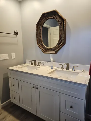 a bathroom with a granite countertop double vanity and mirror