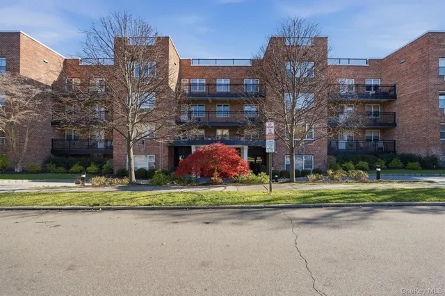a front view of a building with a yard and trees