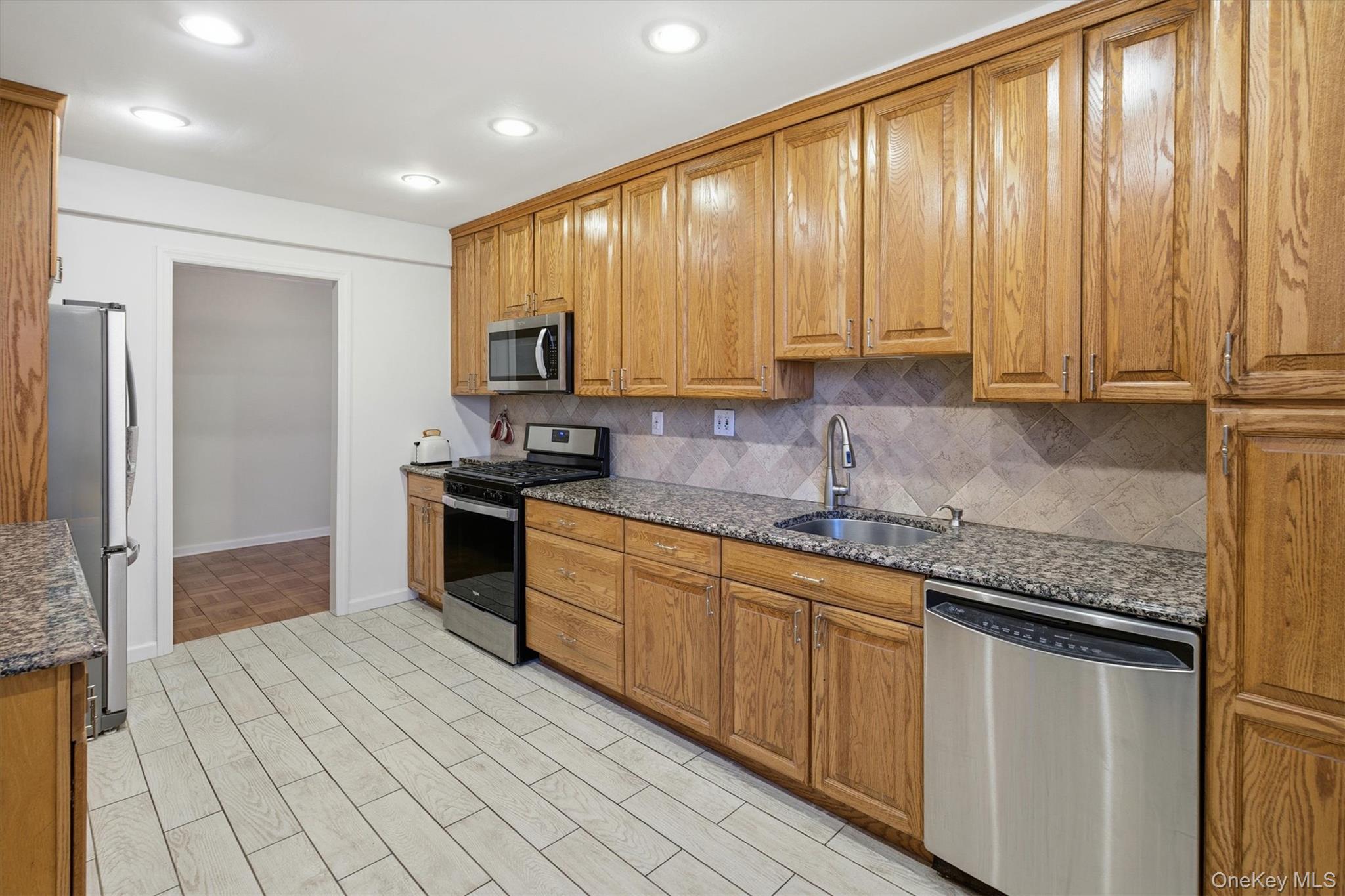 25 Chapel Place, Unit 1B Great Neck, NY 11021 - Photo 10 of 33 a kitchen with stainless steel appliances granite countertop a stove a sink and a refrigerator