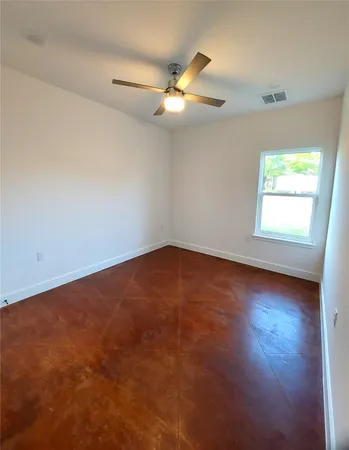 an empty room with a window and a ceiling fan