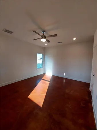 an empty room with a fan & windows