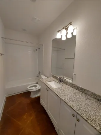 a bathroom with a granite countertop sink a toilet and a mirror
