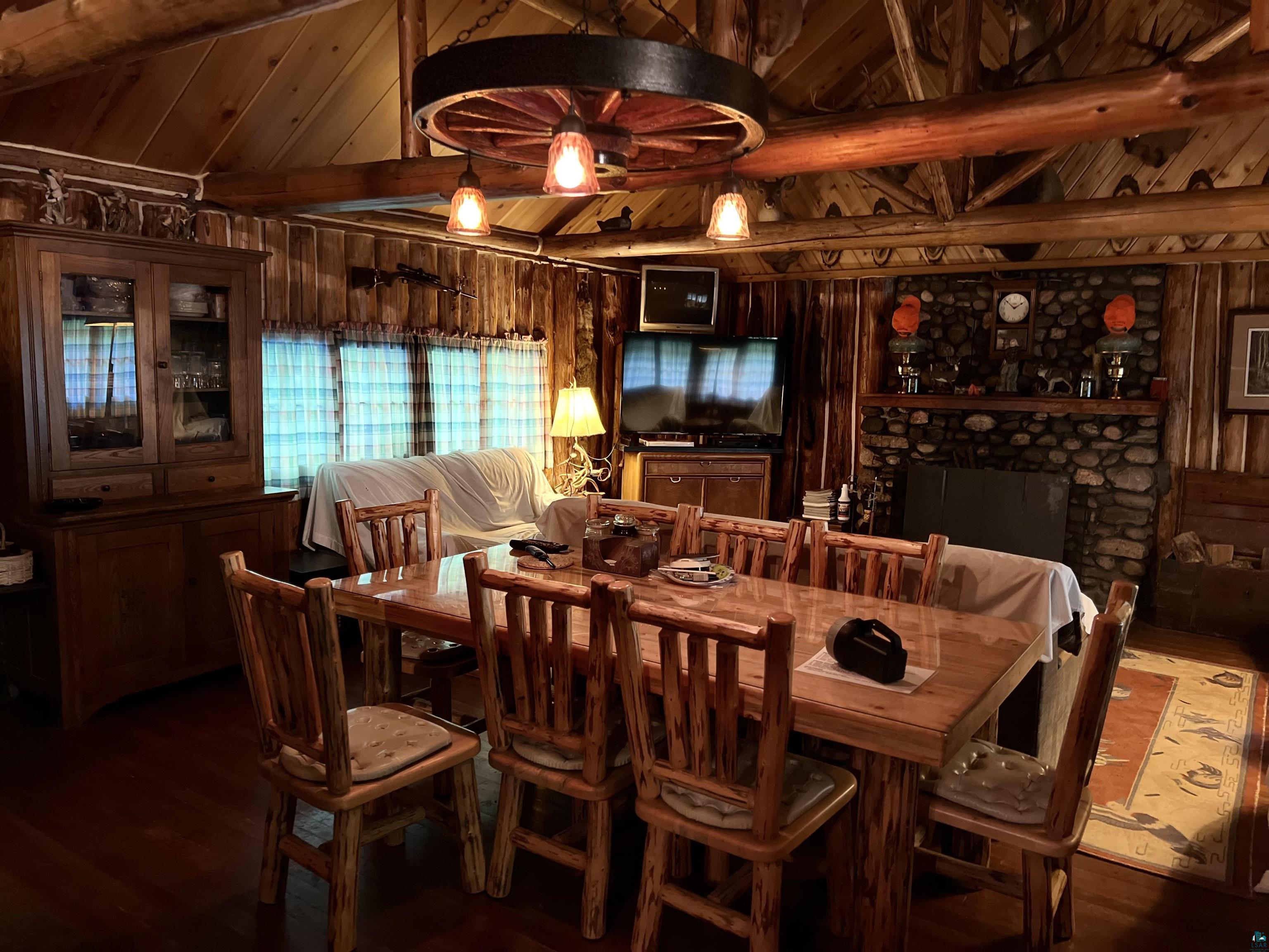 26336 Forest Road 181 Glidden, WI 54527 - Photo 12 of 18 Dining space featuring wood walls, wood-type flooring, a fireplace, and vaulted ceiling with beams
