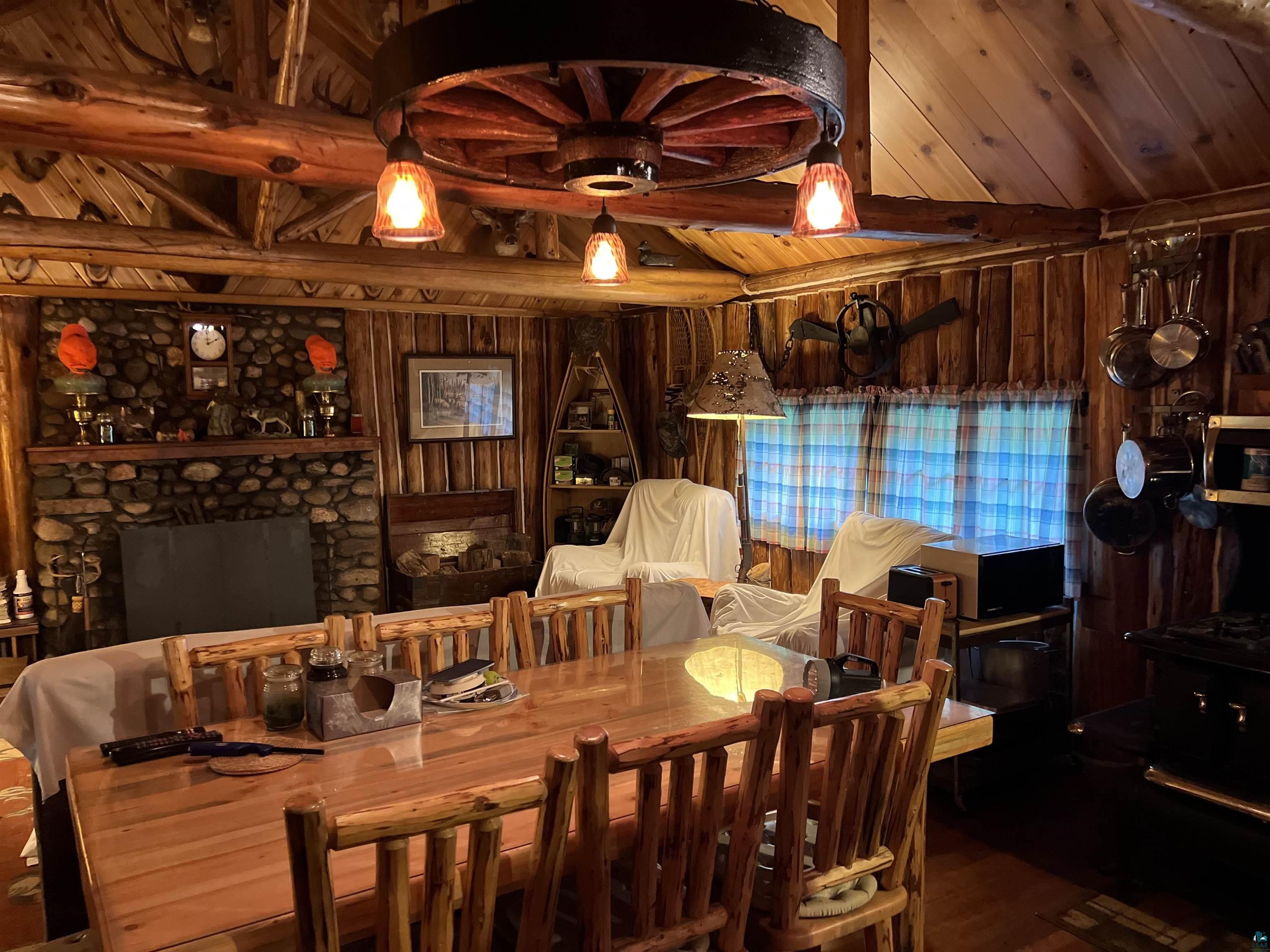 26336 Forest Road 181 Glidden, WI 54527 - Photo 13 of 18 Dining space with a stone fireplace, lofted ceiling, wood walls, wooden ceiling, and wood-type flooring