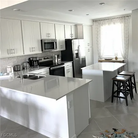 a kitchen with stainless steel appliances a stove a sink a microwave a refrigerator a dining table and chairs