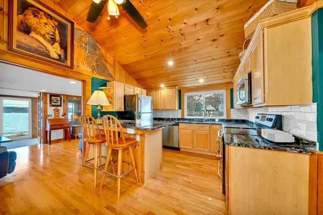 a kitchen with stainless steel appliances granite countertop a stove a refrigerator a sink and dishwasher with wooden floor