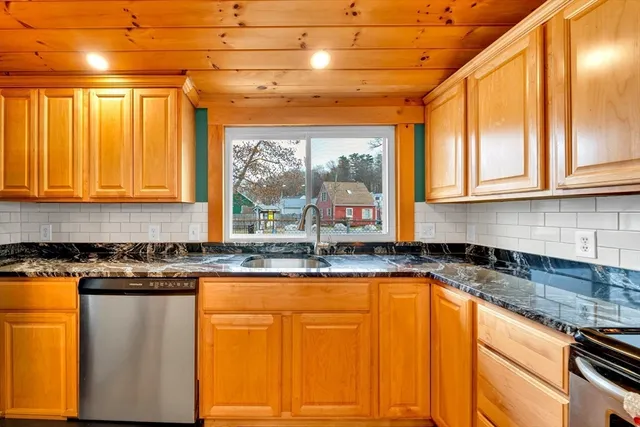 a kitchen with granite countertop wooden cabinets window and stainless steel appliances