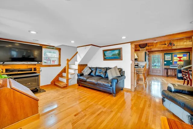 a living room with furniture kitchen view and a wooden floor