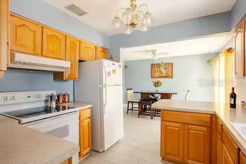 a kitchen with a refrigerator a stove cabinets and a dining table