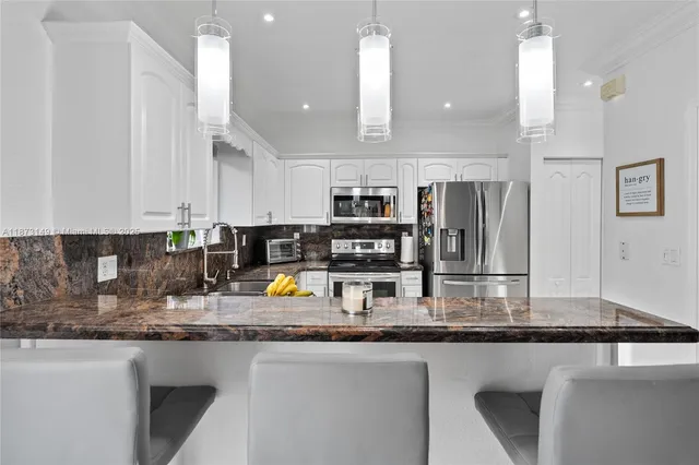 a kitchen with stainless steel appliances granite countertop a sink refrigerator and cabinets