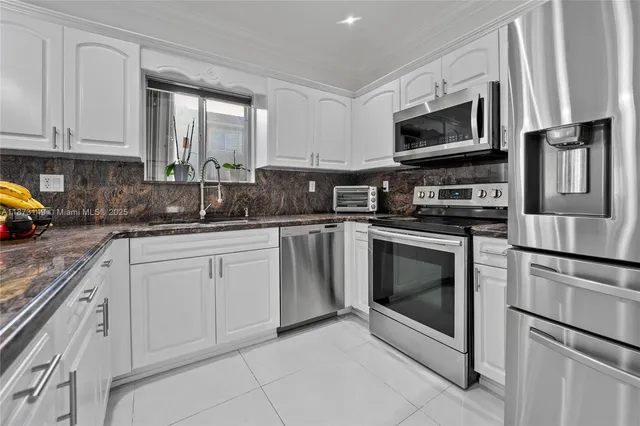 a kitchen with white cabinets stainless steel appliances and a sink