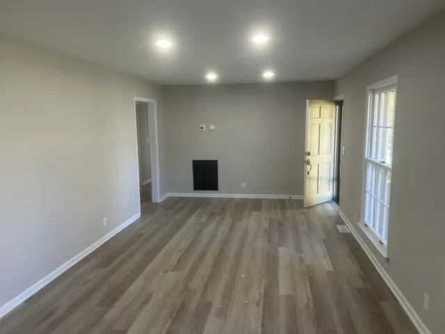 an empty room with wooden floor and windows
