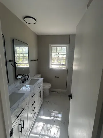 a bathroom with a granite countertop sink mirror vanity and toilet