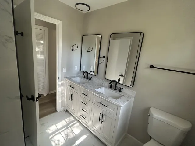 a bathroom with a double vanity sink toilet and mirror