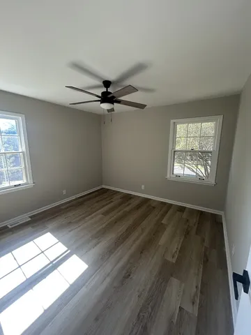 a view of empty room with wooden floor and fan