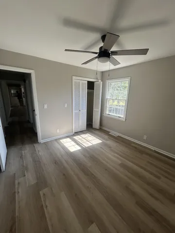 an empty room with wooden floor fan and windows