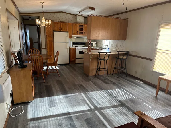 a kitchen with stainless steel appliances kitchen island granite countertop a table chairs and a refrigerator