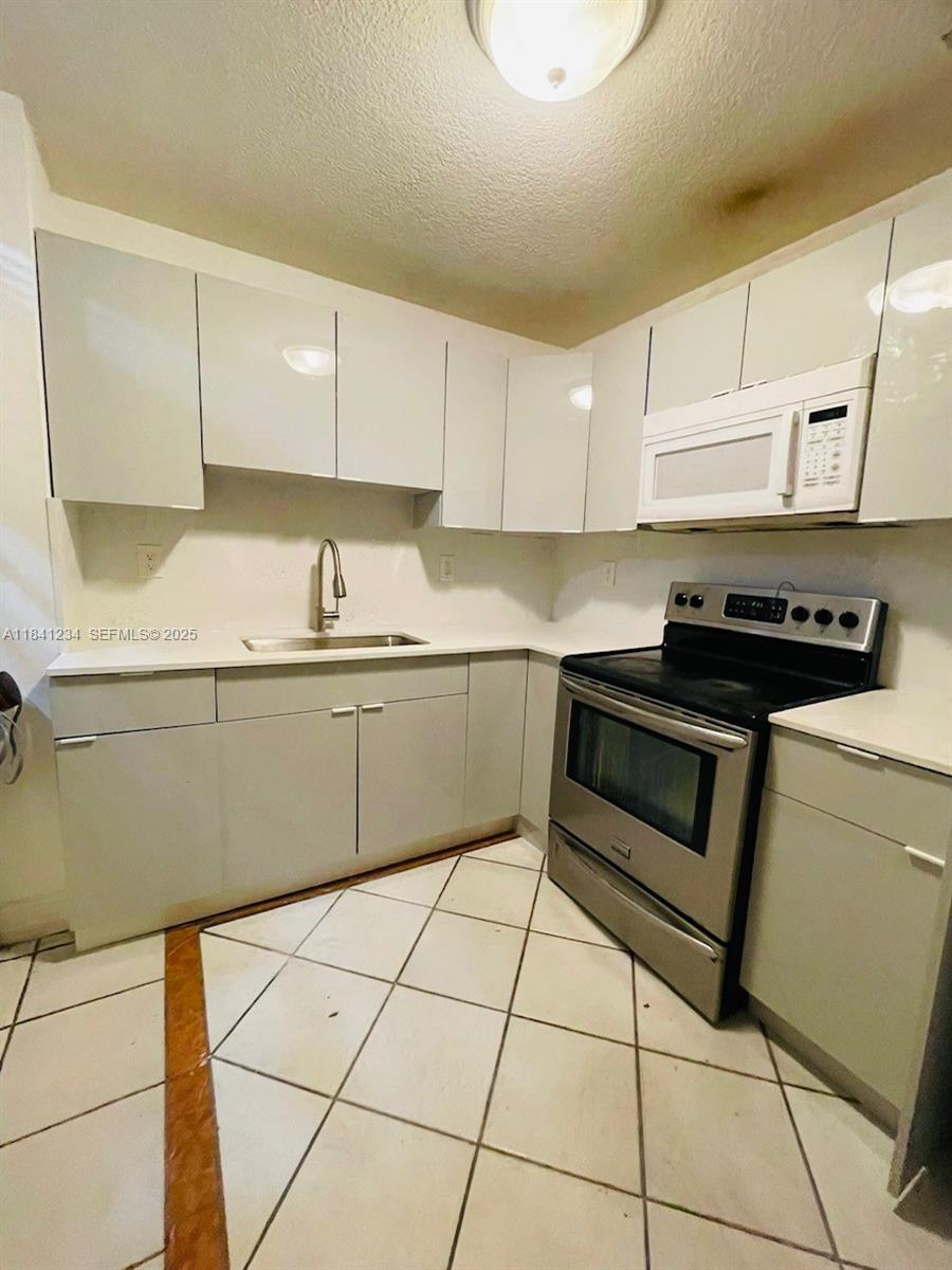 1238 Southwest 4th Street Miami, FL 33135 - Photo 22 of 27 a kitchen with a sink a stove and cabinets