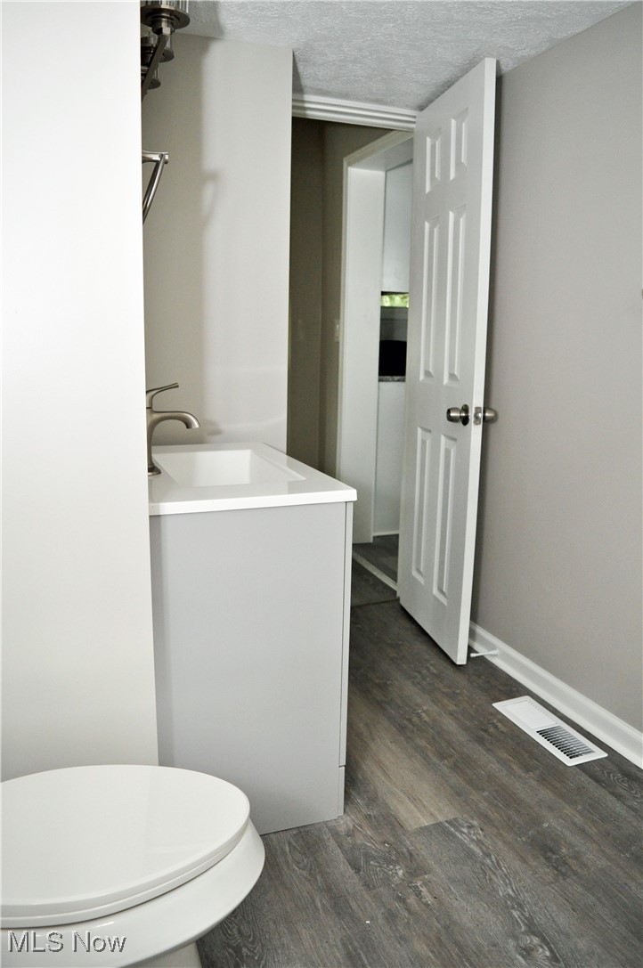7604 Spafford Road Cleveland, OH 44105 - Photo 7 of 23 Bathroom featuring wood finished floors, toilet, a textured ceiling, and vanity