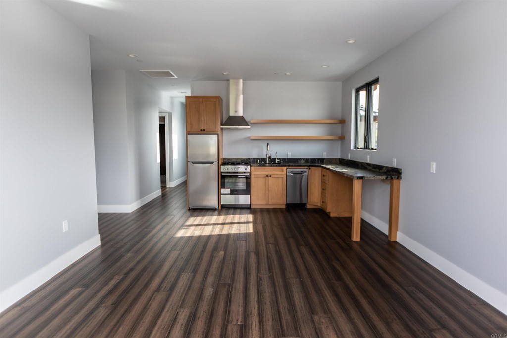 1136 South Coast Highway 101 Encinitas, CA 92024 - Photo 7 of 18 a kitchen with wooden floors and stainless steel appliances