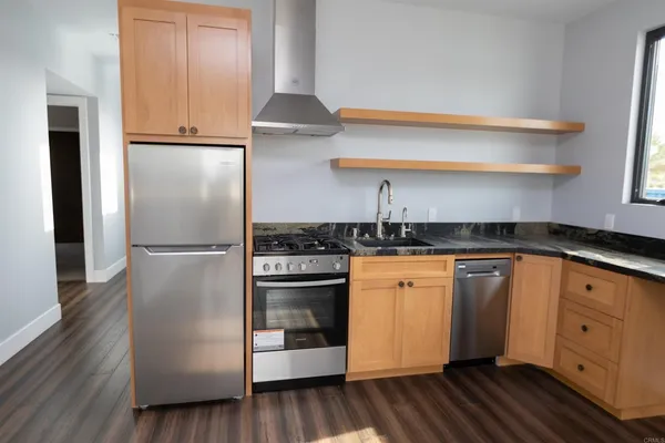 a kitchen with stainless steel appliances granite countertop a refrigerator a stove and white cabinets with wooden floors