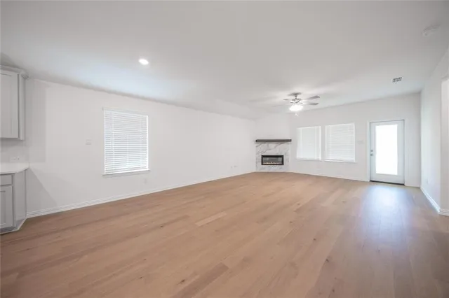 a view of empty room with wooden floor cabinet and windows