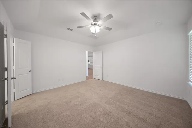 a view of an empty room with a ceiling fan and a window