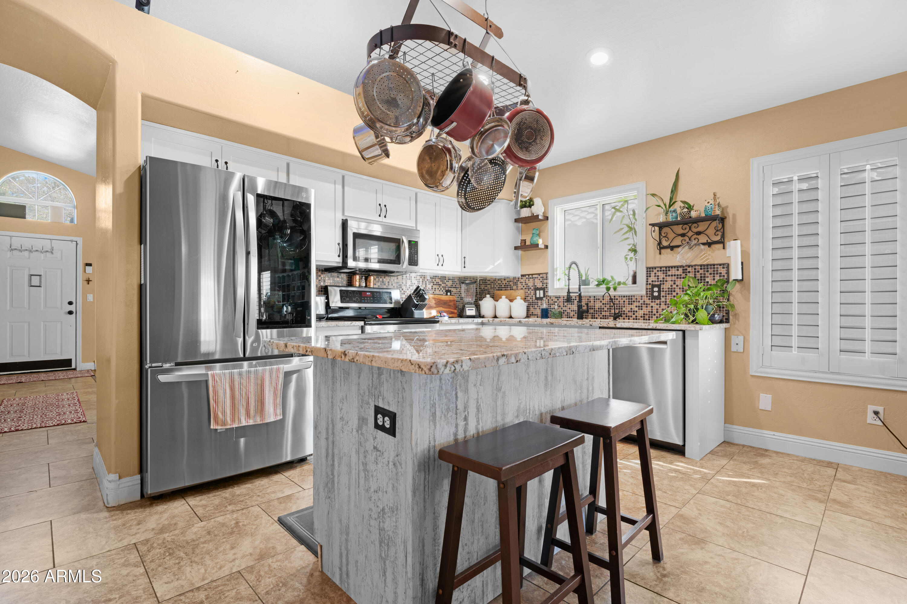 1513 West Shellfish Drive Gilbert, AZ 85233 - Photo 9 of 35 a kitchen with stainless steel appliances granite countertop a refrigerator a stove a sink a dining table and chairs with wooden floor